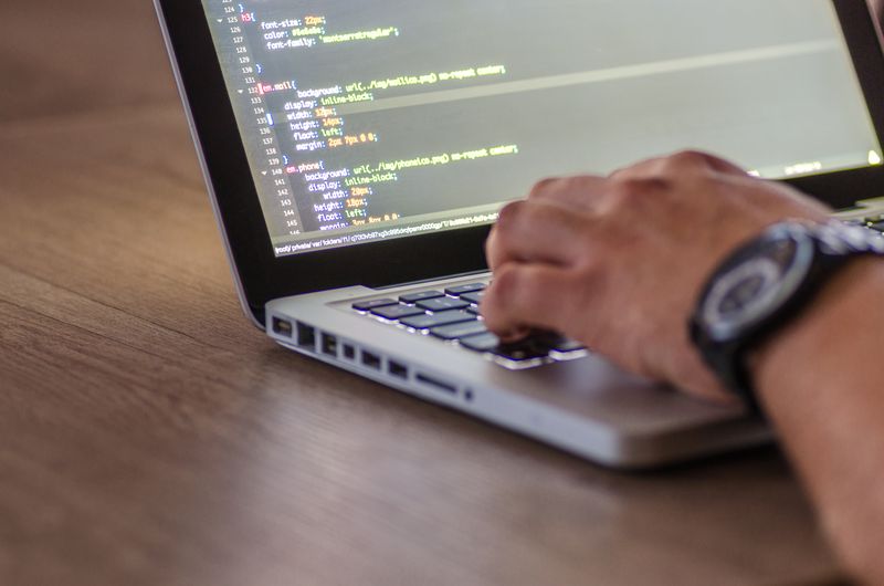 A close-up shot of a person coding on a laptop